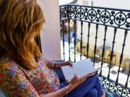 portales inmobiliarios en España. Mujer leyendo en un balcón.