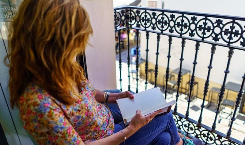 portales inmobiliarios en España. Mujer leyendo en un balcón.