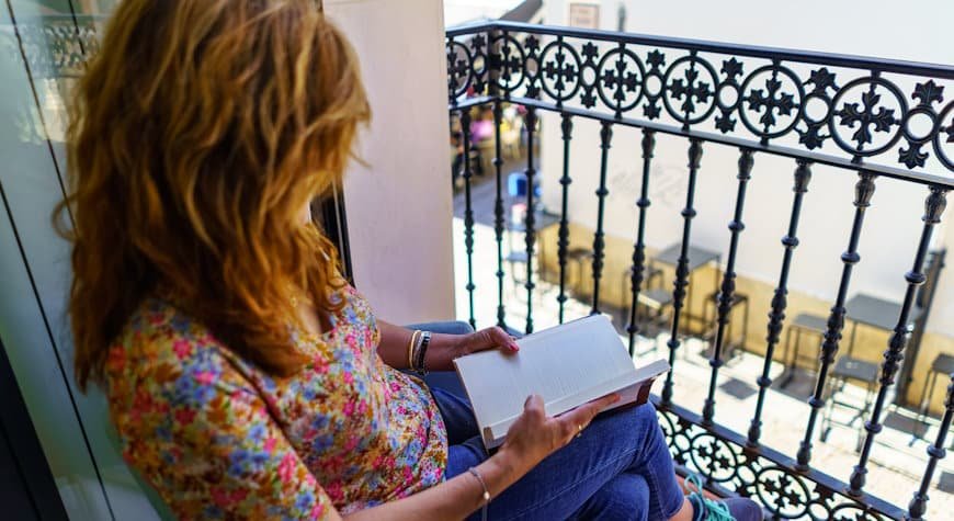 portales inmobiliarios en España. Mujer leyendo en un balcón.