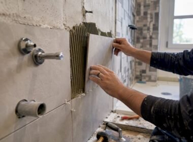 Manos colocando azulejos y accesorios en el baño