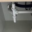 Tuberías y sifón bajo un fregadero en una instalación de fontanería de cocina