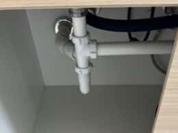 Tuberías y sifón bajo un fregadero en una instalación de fontanería de cocina