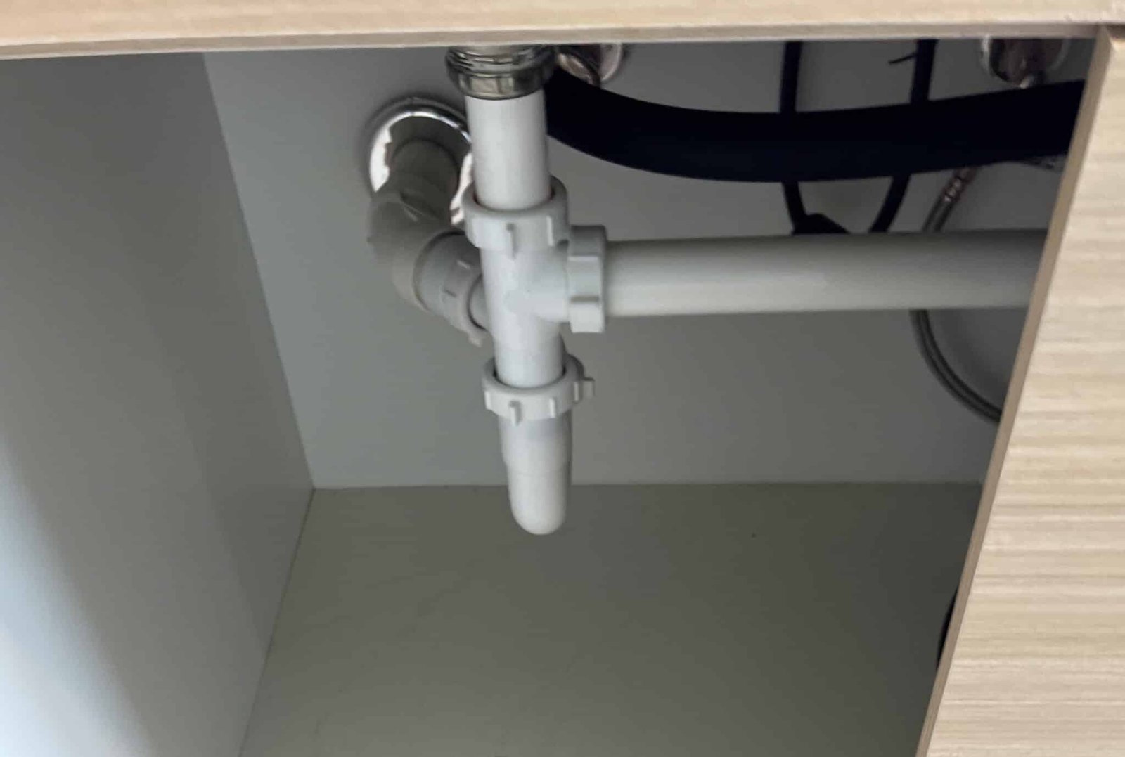 Tuberías y sifón bajo un fregadero en una instalación de fontanería de cocina