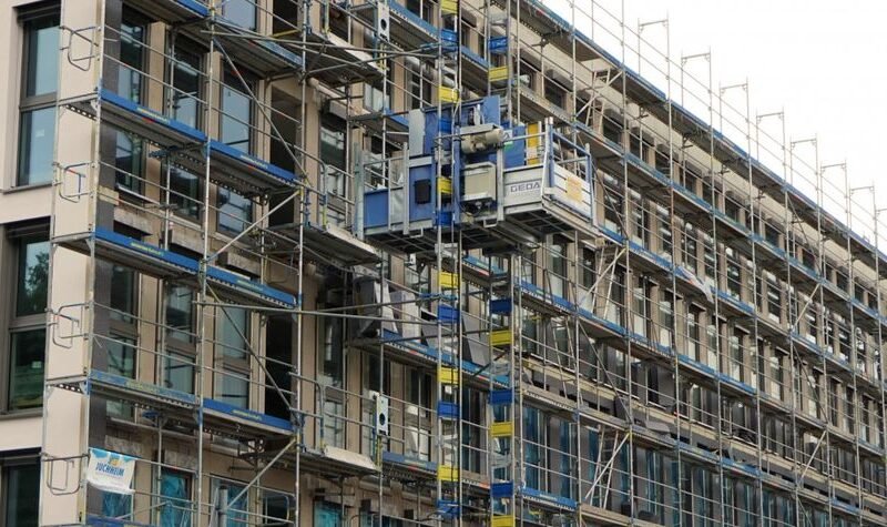 Rehabilitación de fachadas de edificio con andamios y trabajos de renovación